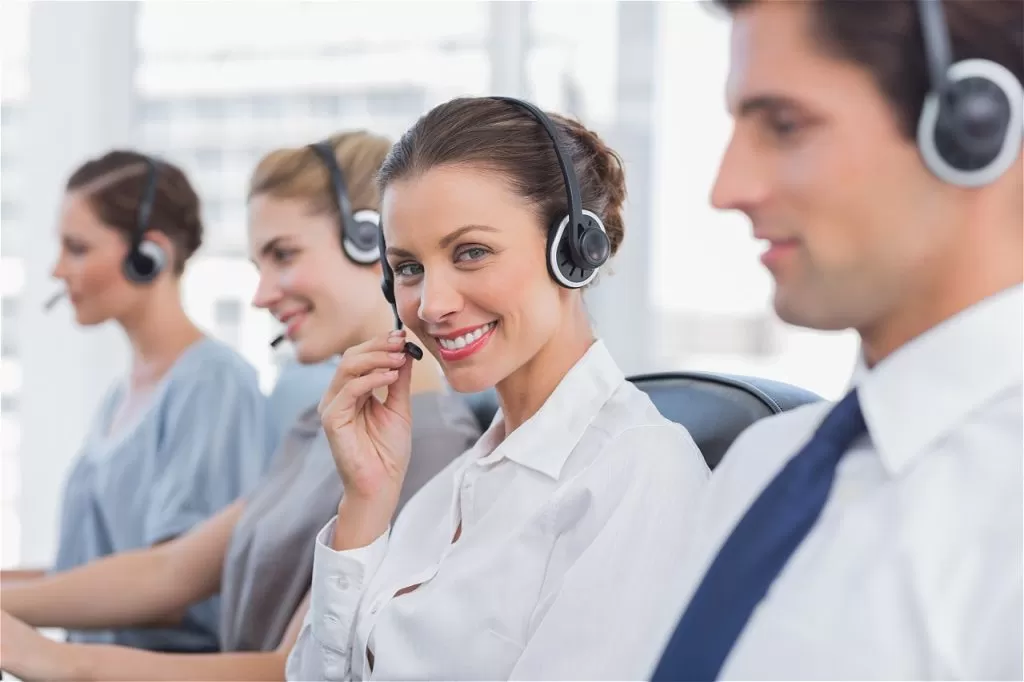 Customer service team with headsets smiling in office