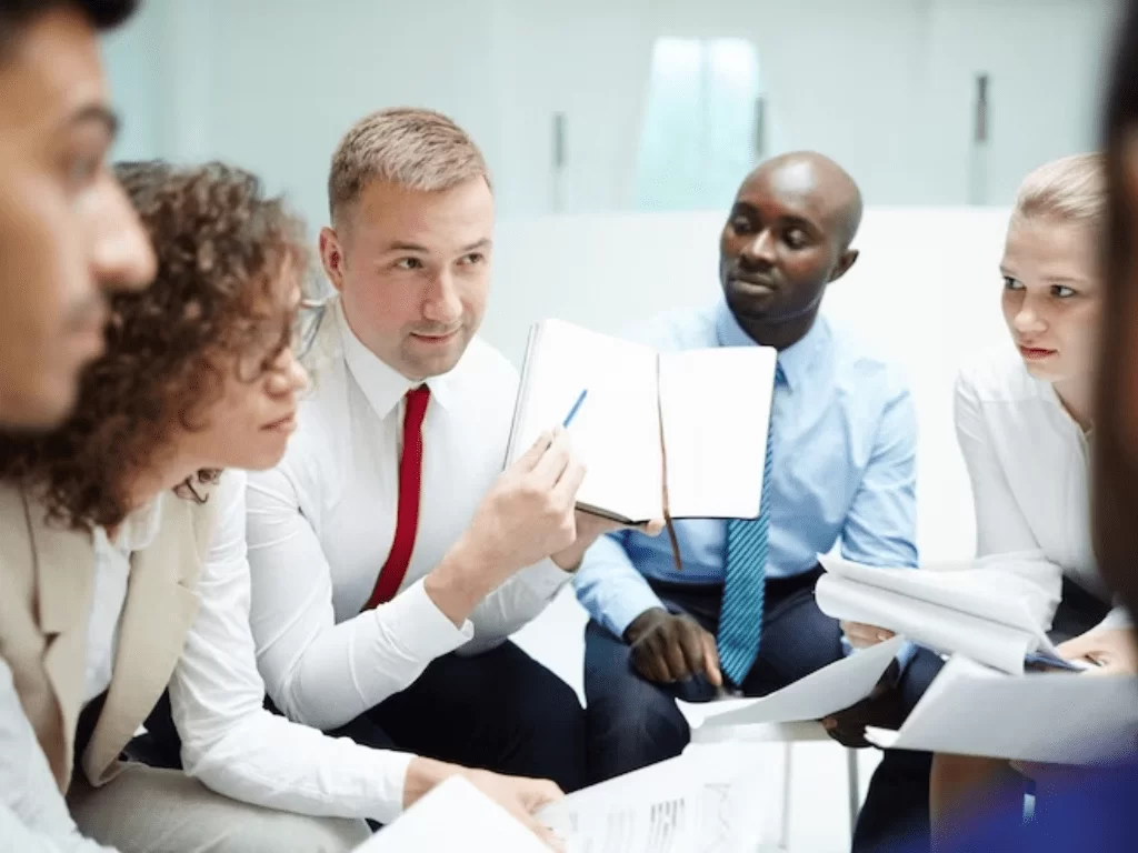 Illustration of a man in red shirt standing behind a pie chart with small human icons on it, symbolizing management and leadership